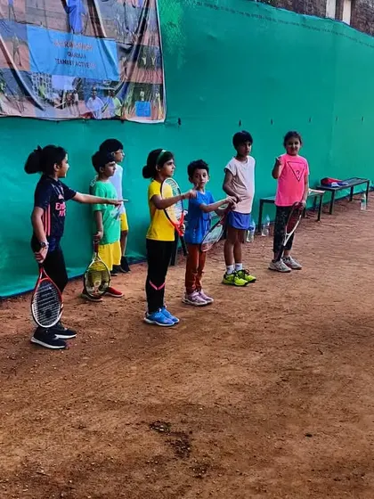Our youngest players, some holding a racket for the first time in a tournament, listening to instructions from our coaching staff. We focus on fundamentals and sportsmanship from day one.