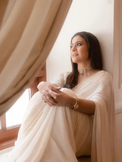 A quiet, contemplative moment by the window. The soft drape of the chiffon saree and the elegant styling create a look that is both sophisticated and deeply personal.