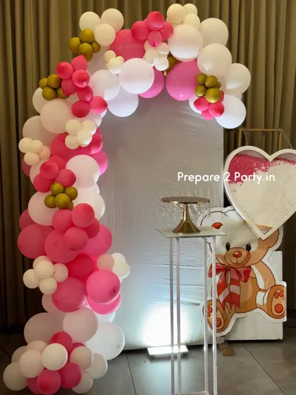 A clear view of the naming ceremony backdrop, featuring a vibrant pink and white balloon arch framing a clean white panel, ready for photos.