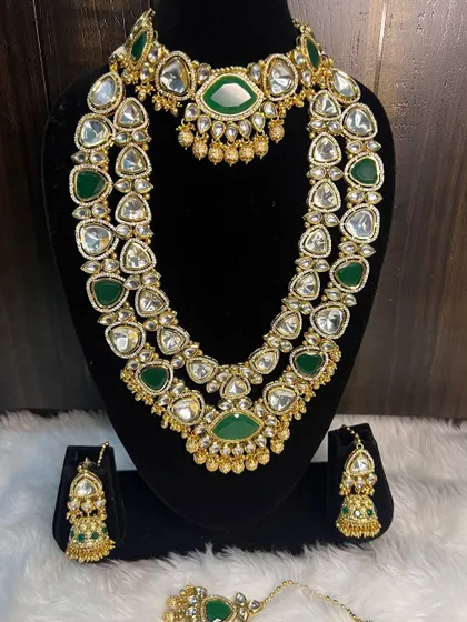 A clear product view of the green Kundan bridal set on a display bust. You can see the quality of the stones and the two distinct necklaces that create a perfect layered look.