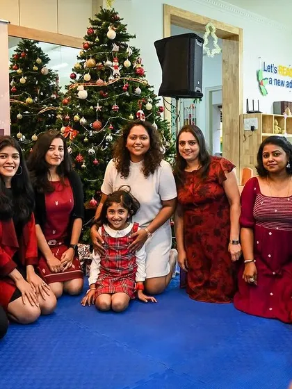 Our team of educators with a student in front of the Christmas tree.