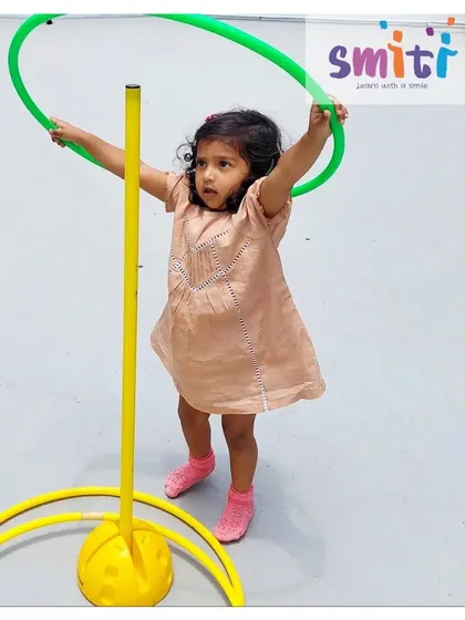 A girl holds a hula hoop, ready for her turn. Simple equipment like hoops and balls can be used for a wide variety of skill-building games.