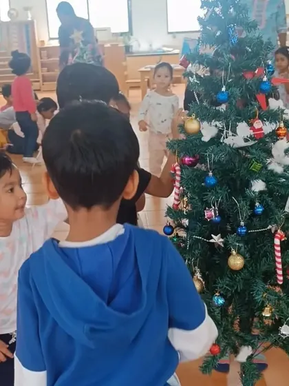 Children gather around the Christmas tree they helped decorate, admiring their handiwork.