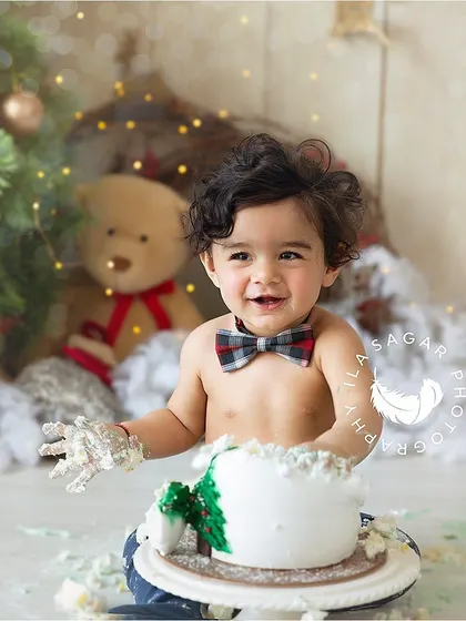 A Christmas-themed cake smash is such a festive way to celebrate a first birthday. The plaid bow tie and holiday backdrop make this session extra special.
