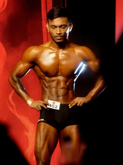 A close-up on stage, showing the sharp abdominal definition and chest fullness required to be competitive.