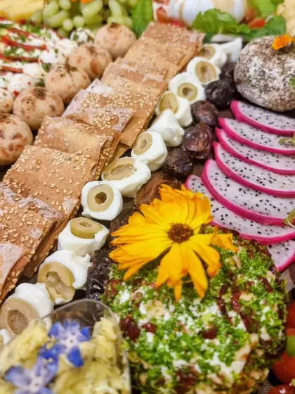 Crackers run through our cheese platter beside fruit, dips and little savoury bites, with flowers adding colour to the board.