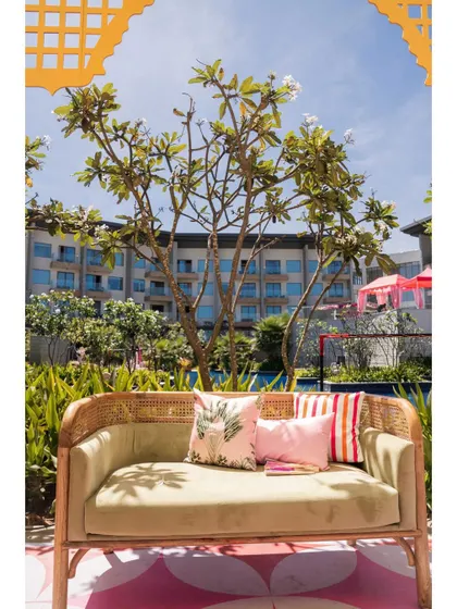 A comfortable and stylish seating area at a Mehendi. The cane sofa with printed cushions is set against a backdrop of the venue, showing how I blend comfort with the overall aesthetic.