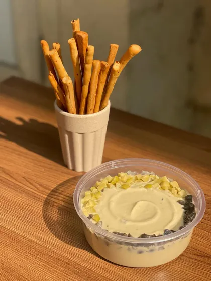 A classic hummus topped with olives and paprika, served with freshly baked breadsticks.