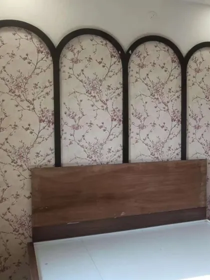 A bedroom featuring an arched wall panel design with a delicate floral wallpaper inside. This is a creative way to use wallpaper as a decorative feature.
