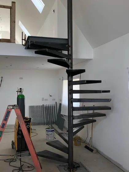 The skeleton of the spiral staircase, fully welded and installed. This forms the foundation for the finished wooden steps and handrail.