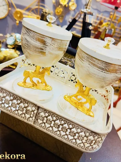 A unique dry fruit box set featuring two containers with a brushed white and gold finish, supported by decorative golden horse stands. This set comes with a patterned metal tray and is a perfect blend of royal and modern design.