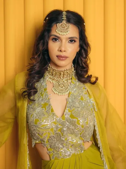 A full view of the green mehendi outfit. The makeup is designed to complement the silver embroidery and the unique colour of the ensemble.