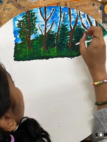 A student works on a landscape painting on a round canvas. Using an unconventional format encourages new ways of thinking about composition.