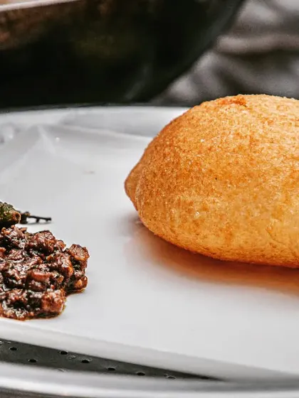 A plate of authentic, spicy Chole with a fluffy, perfectly fried Bhatura. This is the ultimate comfort food, prepared with the traditional Punjabi flavors that everyone craves.