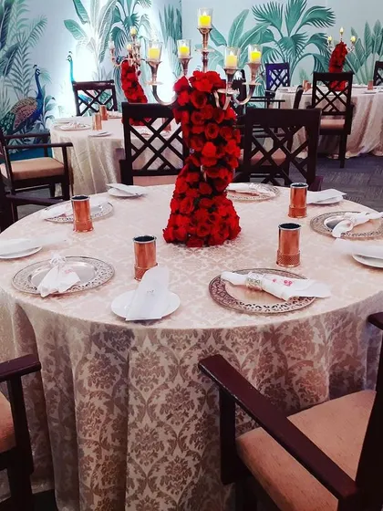 A complete view of a round table setup designed for guest comfort and conversation. The floral centerpiece and quality tableware elevate the dining experience, making guests feel truly special.