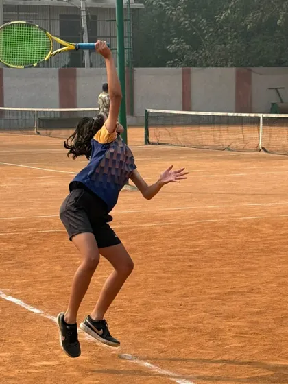 A female player jumping into her serve, generating power from the ground up. This explosive movement is a key part of our athletic development.