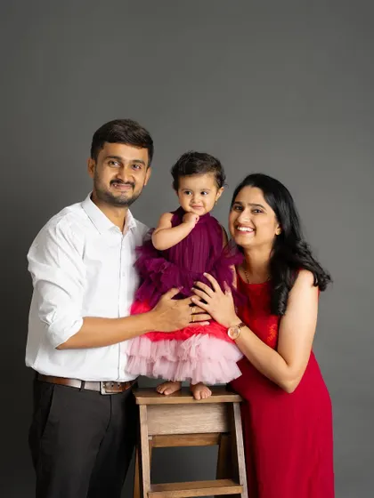 A classic family portrait with a baby girl who is the center of their world. Her sweet, curious expression is simply adorable.