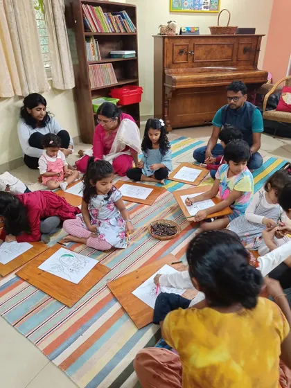 A wider view of the drawing workshop, showing parents assisting their children.
