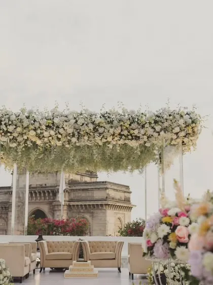 A minimalist mandap with a floating floral canopy of white flowers, offering an uninterrupted view of the Gateway of India, a truly iconic wedding setting.
