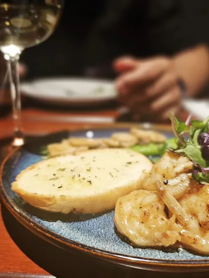 A plate of garlic prawns and a glass of wine. A sustainable lifestyle means making room for moments like these without guilt.