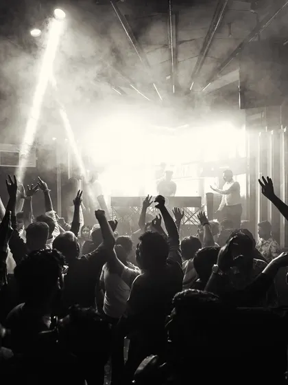 This black and white shot captures the raw energy of the dance floor. The combination of smoke, spotlights, and a crowd with their hands up is the essence of a great club night.