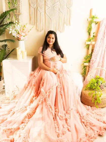 A sweet and simple seated portrait in a peach ruffled gown. The boho setup creates a soft and feminine atmosphere.