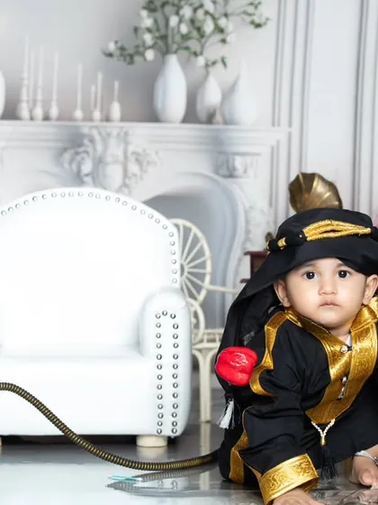 This little guy is taking his sheikh duties very seriously, posing with his hookah in a grand white setting.