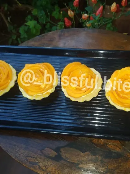 Four of my handcrafted Mango Rose Tartlets on a black platter. The contrast highlights the vibrant color of the fresh mango.