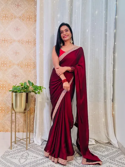 A deep maroon georgette saree with a delicate border. This is a very elegant and sophisticated color, perfect for an evening party or reception.