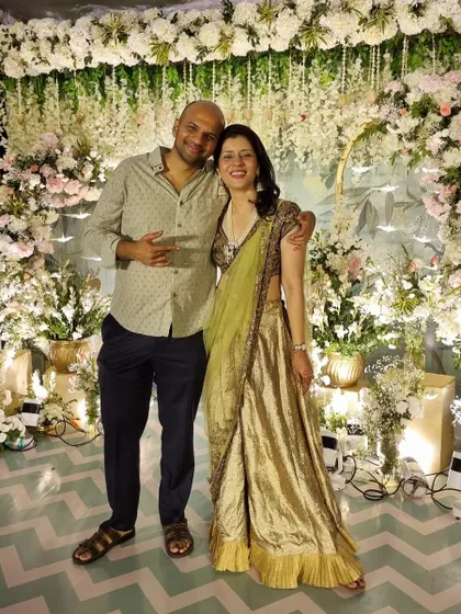 A lovely photo with my husband against a beautiful floral backdrop. I'm wearing a repurposed wedding outfit, combining my Sabya blouse and dupatta with a custom sharara.