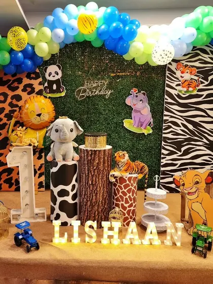A jungle safari theme for a first birthday, incorporating elements from The Lion King and other wild animals against a greenery and animal-print backdrop.