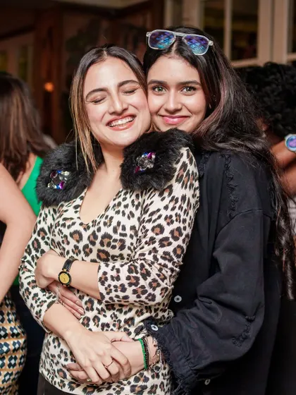 Friends staying warm and stylish in animal print, hugging it out on the dance floor during our December party.