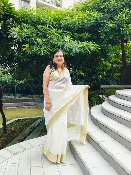 A full look of the client in her beautiful white Kasavu saree, paired with the custom purple blouse and traditional gold jewelry.