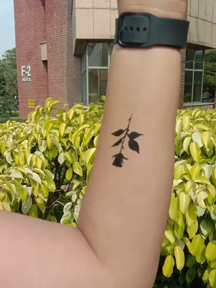 A minimalist black rose silhouette painted on the forearm. This is a great example of a simple yet elegant temporary tattoo.