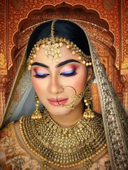 A fusion bridal look that blends tradition with a touch of modern color. The soft blue on the eyelid adds an unexpected yet beautiful element to the warm, neutral tones of the overall makeup.