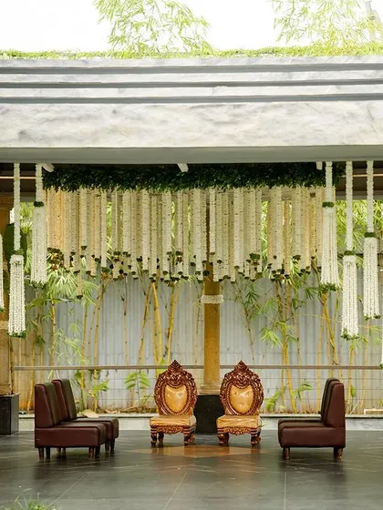 A view of the Prangana Venue mandap from the side, showing the elegant seating and the way the white and green color palette complements the natural surroundings. The rainproof tent ensures the celebration continues, no matter the weather.