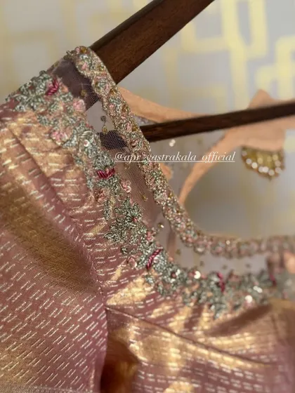 A dusty pink blouse with a sheer net yoke, adorned with delicate floral embroidery. This is a more contemporary take on the traditional bridal blouse.