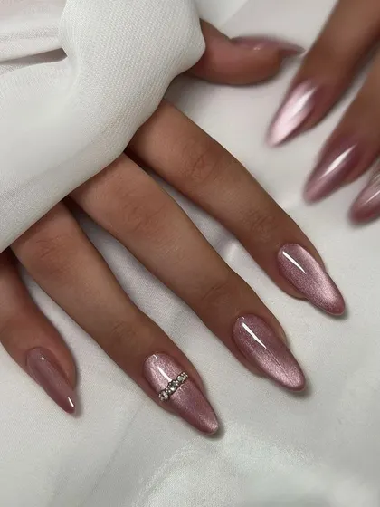 Soft, elegant, and shimmery. This beautiful pink cat-eye polish on long stiletto nails is accented with a simple line of rhinestones for an extra touch of glamour.
