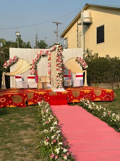The complete outdoor Nikah stage with a pink carpet aisle lined with flowers. The setup is perfect for a garden wedding ceremony.