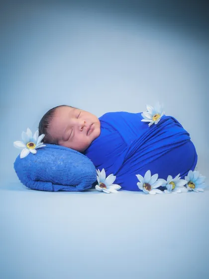 A wider view of the "potato sack" pose. The simple, clean background keeps all the focus on the beautifully wrapped baby.