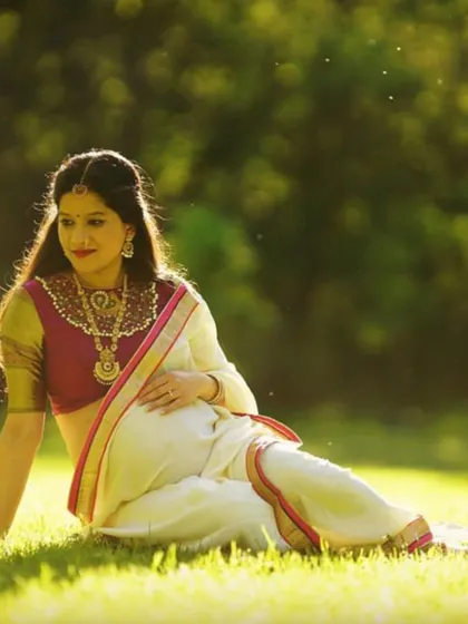 A beautiful maternity shoot featuring our client in a traditional white and pink saree, looking serene and goddess-like.