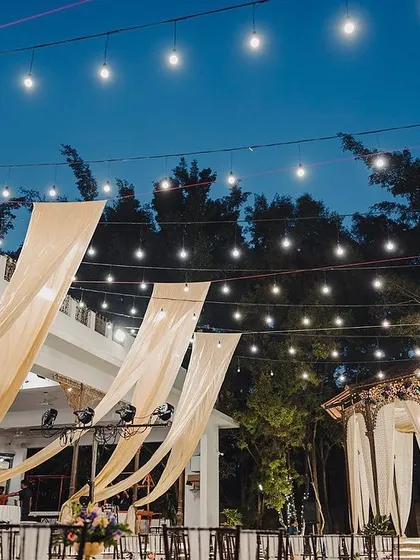Flowing drapes and strings of lights create a dramatic and festive ceiling treatment for the outdoor Sangeet venue.