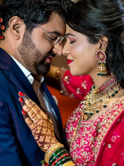 A close-up, intimate portrait showing the couple's deep connection. The focus is on the bride's intricate mehndi and the couple's gentle embrace.