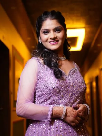 A close-up portrait of the bride, showing her bright smile and the beautiful purple-toned makeup.