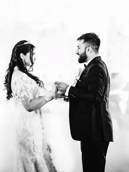 A quiet moment amidst the celebration. This black and white photo shows the couple holding hands during their first dance, surrounded by soft fog.