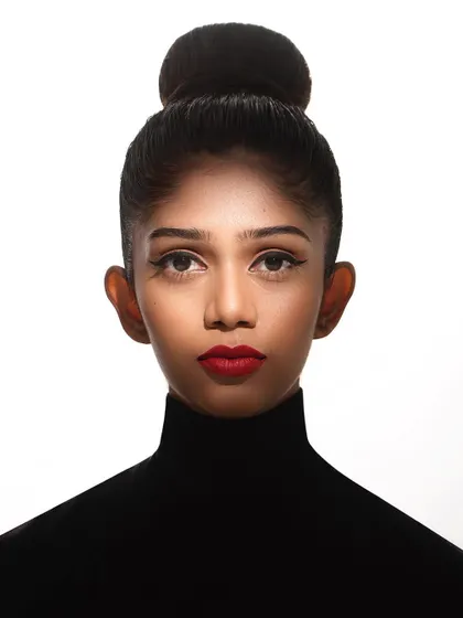 A powerful, clean headshot is essential for any model's portfolio. This image showcases a classic, high-fashion look with a tight bun, sharp cat-eye liner, and bold red lips. The high-key lighting ensures the focus remains entirely on the model's strong features and direct gaze.