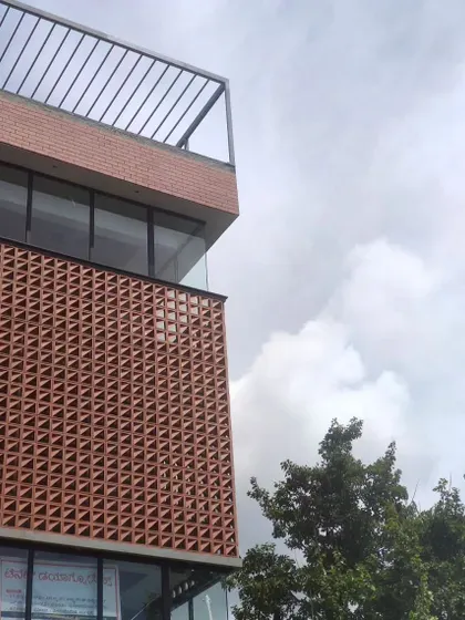The triangular terracotta blocks create a dynamic and porous skin for the building, providing shade and ventilation.