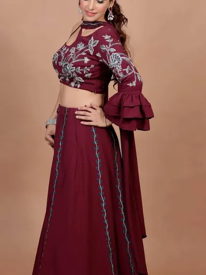 A side view of the maroon Indo-Western lehenga, showing the beautiful floral embroidery and the unique one-sleeve design with a ruffled cuff. It's a perfect blend of traditional motifs and contemporary style.