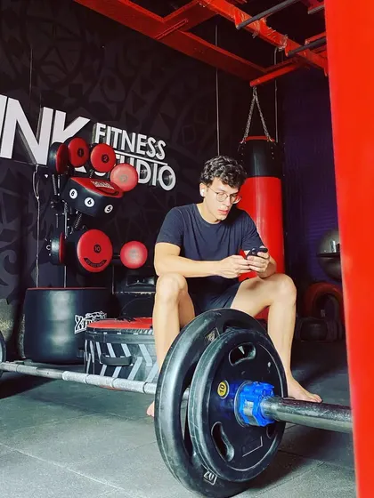 A client taking a break, sitting on a barbell. Our studio is a place where you can feel comfortable and at ease, even during the toughest workouts.