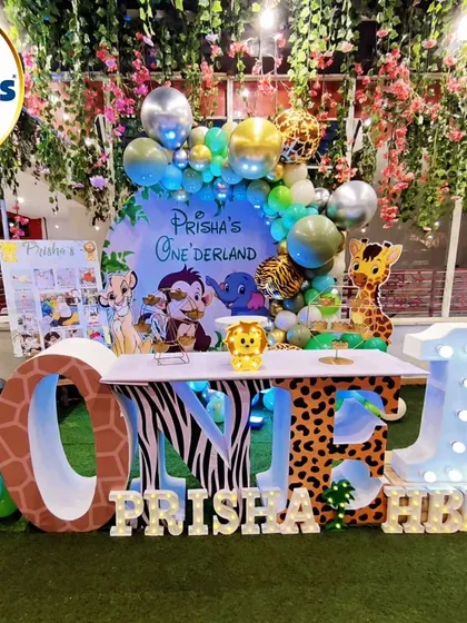 A beautiful jungle-themed party set under a canopy of flowers and lights. The 'ONE' marquee table and animal cutouts create a magical 'Onederland'.